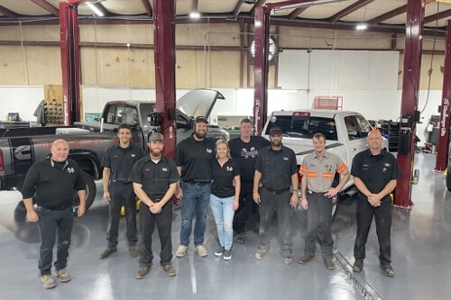 New Year, New State-of-the-Art Diesel Service and Repair Facility in Brooksville, FL with RDI Power; image of RDI team standing in new shop bay with diesel pickup trucks on lifts behind them