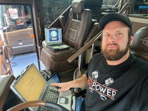 Bus Service & Repair | RDI Power in Brooksville, FL. Image of an RDI Power mechanic inside a bus on a driver’s seat doing vehicle diagnostics.