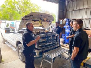 How to Increase Fuel Mileage | RDI Power in Brooksville, FL. Image of 4 auto technicians and a white Ford F-250 with hood up in an auto shop garage.