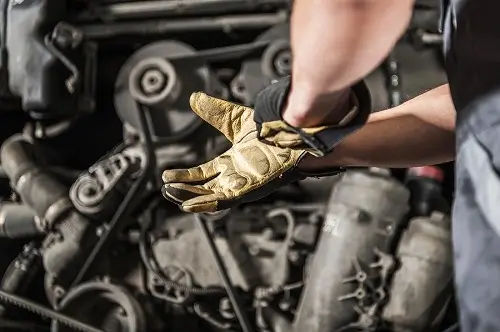 Are Diesel Engines More Expensive to Repair & Maintain? | RDI Power in Brooksville, FL. Closeup image of a mechanic wearing his gloves in preparation for heavy-duty diesel engine repair work.
