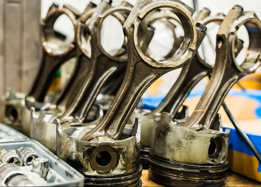 Light-duty diesel repair,uto repair in Brooksville, FL by RDI Power. Image of multiple engine pistons with connecting rods placed on a workbench, highlighting precision engine repair and commitment to vehicle performance.