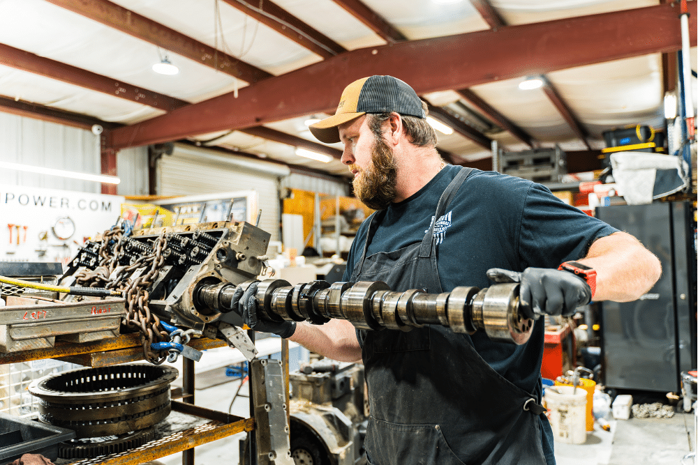Diesel Engine in Brooksville, FL by RDI Power. Mechanic inspecting and removing a camshaft from a diesel engine inside a workshop.