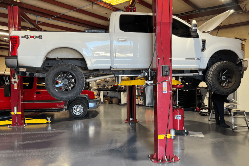 10R140 Transmission, diesel repair in Brooksville, FL at RDI Power. A white Ford truck on a hydraulic lift inside a professional repair shop, undergoing maintenance and transmission service.